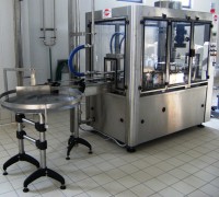 Riempitrice particolare su tavolo appoggio uscita bottiglie